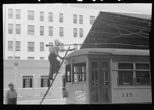 Workman climbing on top of streetcar to change wheel on trolley. Streetcar terminal, Oklahoma City, Oklahoma