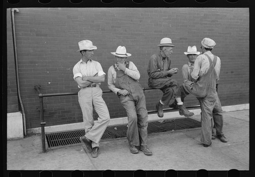 Group of men talking while sitting and leaning on railing, Muskogee, Oklahoma