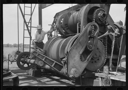 Cable tool equipment with operator. Oil well near Saint Louis, Oklahoma. This is equipment used in drilling