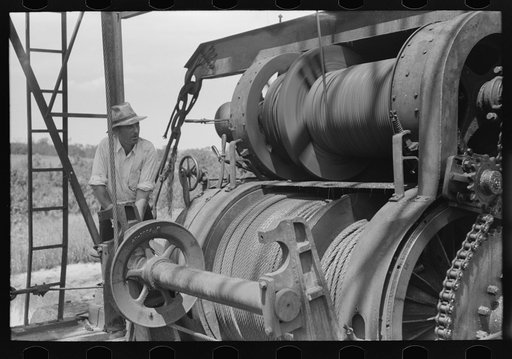 Untitled photo, possibly related to: Roughneck tying piece of string around cable to determine depth to which bailer is being lowered. Oil well near Seminole, Oklahoma