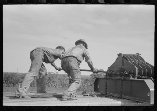Unloading heavy equipment from truck, Seminole oil field, Oklahoma
