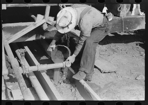 Oil field worker examining mud to determine characteristics of stratum through which drilling is being done, Seminole oil field, Oklahoma
