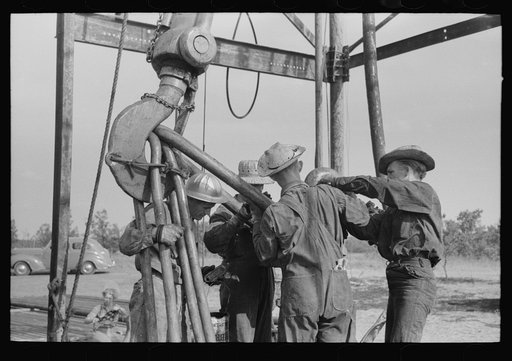 Oil workers working on lowered traveling block, Seminole oil field, Oklahoma