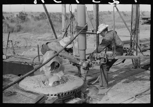 Adding a length of drilling pipe at oil well in Seminole oil field, Oklahoma. Wrench applied to loosen pipe