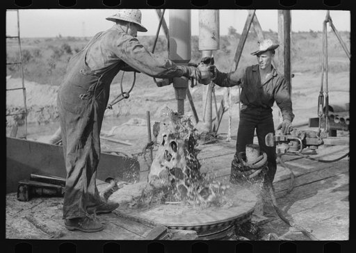 Adding a length of drilling pipe at oil well in Seminole oil field, Oklahoma. Mud spurting out as section of pipes are loosened