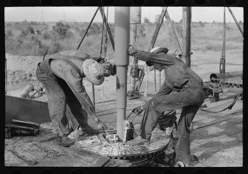 Adding a length of drilling pipe at oil well in Seminole oil field, Oklahoma. Clamps are put in place
