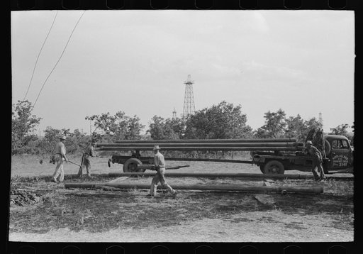 Untitled photo, possibly related to: Unloading pipe from truck at oil well, Seminole oil field, Oklahoma