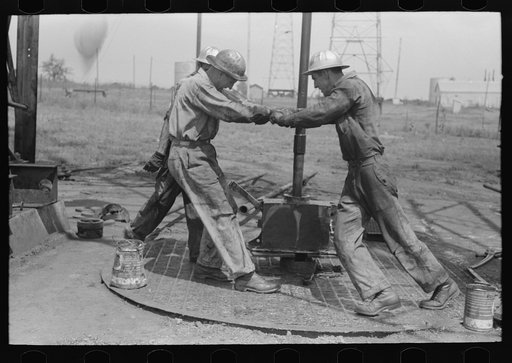 Roughnecks leaning on the wrench to tighten the joint in the pipe, oil well, Oklahoma City, Oklahoma