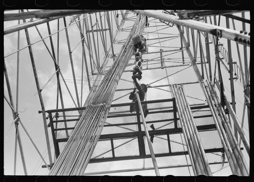 Untitled photo, possibly related to: Looking up in an oil derrick. Roughneck inserting lengths of pipe into the elevator for pulling the casings. Oklahoma City, Oklahoma