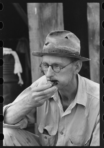 Roustabout taking chew of tobacco, Seminole oil field, Oklahoma