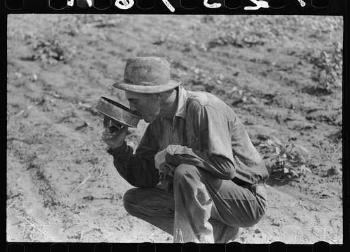 Roustabout in the oil fields drinking water from the top of a five-gallon can. Seminole oil field, Oklahoma