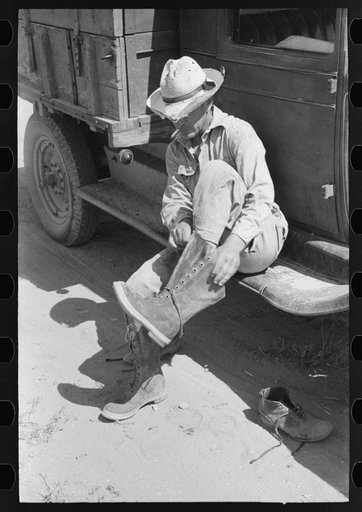 Mr. Johnson, FSA (Farm Security Administration) client with part interest in cooperative well, putting on his boots, near Syracuse, Kansas