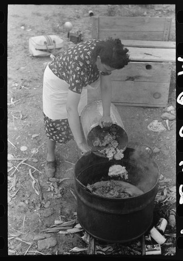 Spanish-American FSA (Farm Security Administration) client emptying pail of grease into kettle for purpose of making soap, Taos County, New Mexico