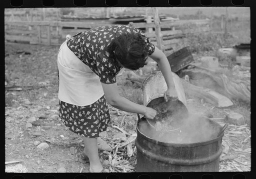 Untitled photo, possibly related to: Spanish-American FSA (Farm Security Administration) client emptying pail of grease into kettle for purpose of making soap, Taos County, New Mexico