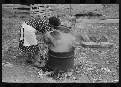 Untitled photo, possibly related to: Spanish-American FSA (Farm Security Administration) client emptying pail of grease into kettle for purpose of making soap, Taos County, New Mexico