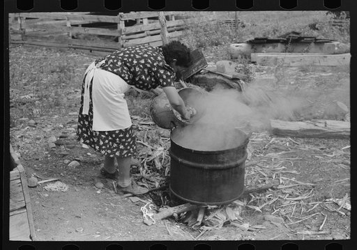 Untitled photo, possibly related to: Spanish-American FSA (Farm Security Administration) client emptying pail of grease into kettle for purpose of making soap, Taos County, New Mexico