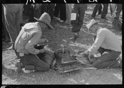 Contestant at Bean Day rodeo examining saddle, Wagon Mound, New Mexico