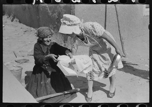 Seventy-five-year-old Spanish-American woman taking loaf of bread to place in outdoor earthern oven for baking, Taos County, New Mexico