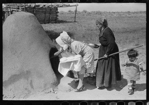 Untitled photo, possibly related to: Spanish-American woman putting loaf of bread into oven, Taos County, New Mexico