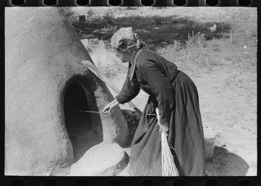 Determining temperature of earthen oven in which bread will be baked by seeing how fast straw will be burned, Taos County, New Mexico