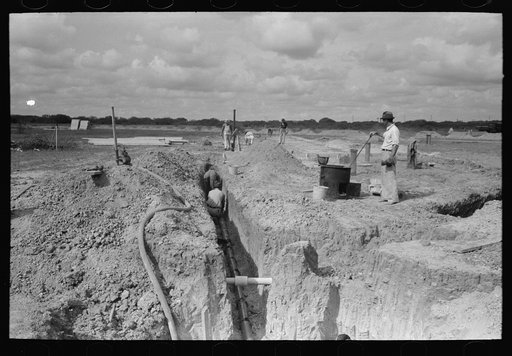 Laying sewer pipe at migrant camp under construction at Sinton, Texas
