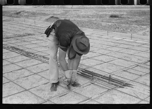 Untitled photo, possibly related to: Tying iron reinforcement bars together before pouring concrete at migrant camp under construction at Sinton, Texas