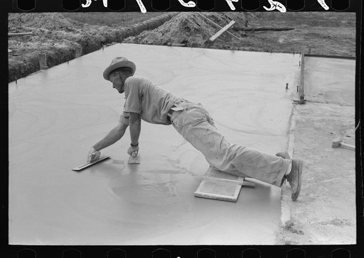 Smoothing concrete floor at migrant camp under construction at Sinton, Texas