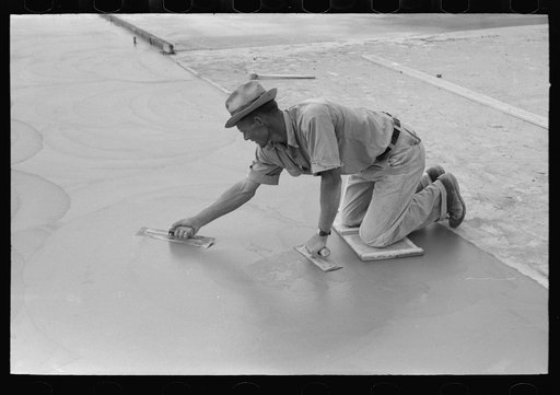 Smoothing concrete floor at migrant camp under construction at Sinton, Texas