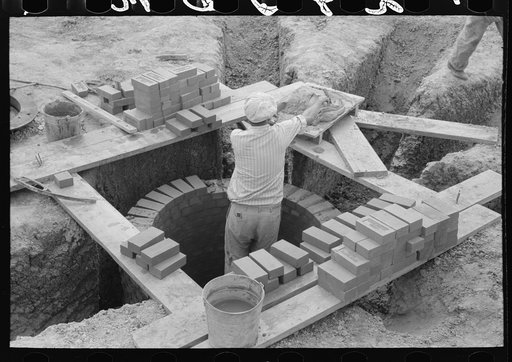 Laying bricks in construction of manhole at migrant camp at Sinton, Texas