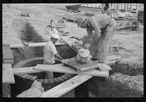 Laying bricks in construction of manhole at migrant camp, Sinton, Texas