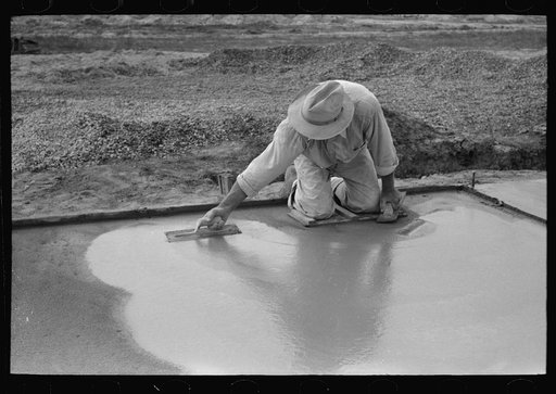 Smoothing concrete floor in construction of migrant camp, Sinton, Texas