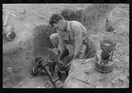 Soldering a joint of cast iron sewer pipe at migrant camp under construction at Sinton, Texas