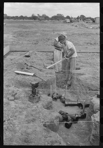 Untitled photo, possibly related to: Soldering a joint of cast iron sewer pipe at migrant camp under construction at Sinton, Texas