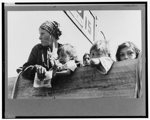 Mexican woman and children looking over side of truck which is taking them to their homes in the Rio Grande Valley from Mississippi where they have been picking cotton. Filling station, Neches, Texas
