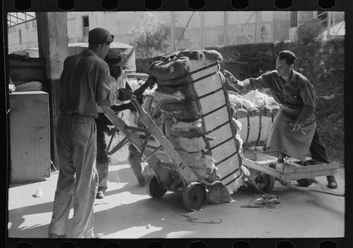 Loading bale of cotton onto hand truck at platform. Cotton compress, Houston, Texas