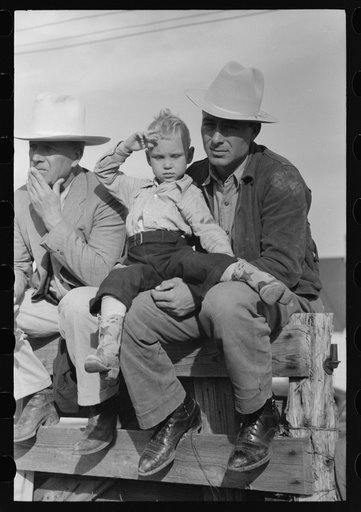 West Texan and his son sitting on fence at horse auction, Eldorado, Texas