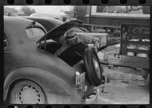 Untitled photo, possibly related to: Loading empty milk cans into back of car, creamery, San Angelo, Texas