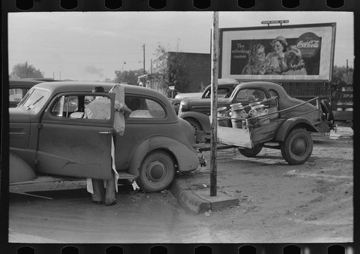 Untitled photo, possibly related to: Loading empty milk cans into back of car, creamery, San Angelo, Texas