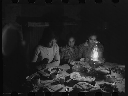 Part of Pomp Hall's family eating supper by lamplight, Creek County, Oklahoma. See general caption number 23