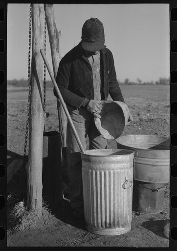 Untitled photo, possibly related to: Pouring bran into can for mixing into a mash for the hogs. Sons of Pomp Hall, Negro tenant farmer, Creek County, Oklahoma. See general caption number 23