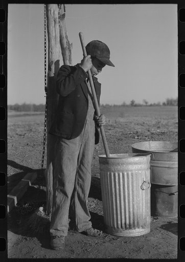 Untitled photo, possibly related to: Pouring bran into can for mixing into a mash for the hogs. Sons of Pomp Hall, Negro tenant farmer, Creek County, Oklahoma. See general caption number 23