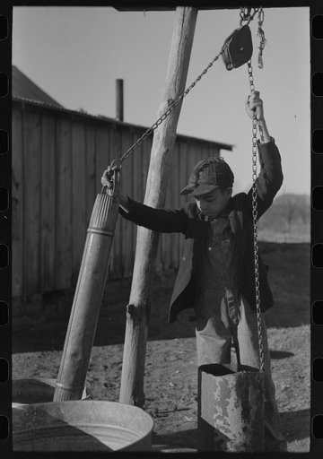Untitled photo, possibly related to: Pouring bran into can for mixing into a mash for the hogs. Sons of Pomp Hall, Negro tenant farmer, Creek County, Oklahoma. See general caption number 23