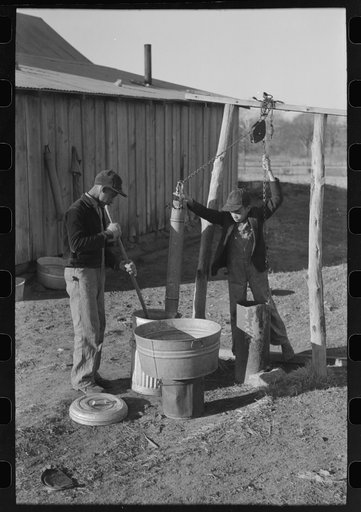 Untitled photo, possibly related to: Pouring bran into can for mixing into a mash for the hogs. Sons of Pomp Hall, Negro tenant farmer, Creek County, Oklahoma. See general caption number 23