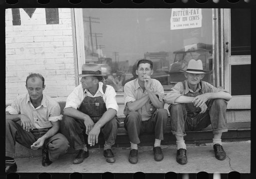 Men sitting along sidewalk in farm marketing section of Muskogee, Oklahoma
