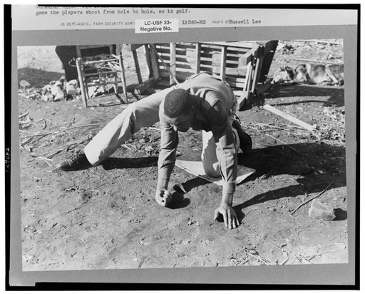 Negro playing marbles on the first warm day in the spring. In this game the players shoot from hole to hole, the same idea as in golf or miniature golf. Eufaula, Oklahoma