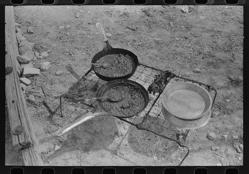 Noonday meal of professional goat and sheep shearers cooking over the campfire; pinto beans are a main item in thier diet. Ranch of rehabilitation borrower in Kimble County, Texas