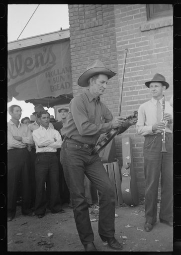 Member of orchestra which plays outside grocery store on Saturday afternoon tuning his violin, Phoenix, Arizona
