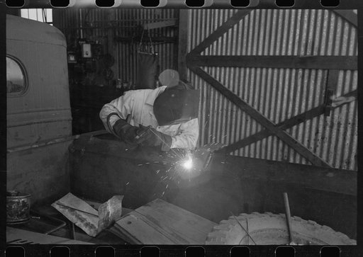 Untitled photo, possibly related to: The United Producers and Consumers Cooperative maintains an automobile repair shop. In this picture, a worker is repairing a farmer's truck with an electric welder. Phoenix, Arizona