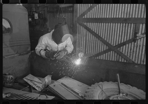The United Producers and Consumers Cooperative maintains an automobile repair shop. In this picture, a worker is repairing a farmer's truck with an electric welder. Phoenix, Arizona