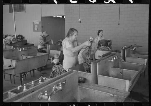 Wives of migratory workers in the laundry room at the Agua Fria Migratory Labor Camp, Arizona. Hot and cold water are furnished by the camp, soap and other washing materials by the people